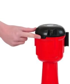 Osoba naciska przycisk na czerwonym sygnalizatorze awaryjnym, który może być używany w sytuacjach kryzysowych. Urządzenie służy do poprawy bezpieczeństwa pracy oraz ochrony środowiska.