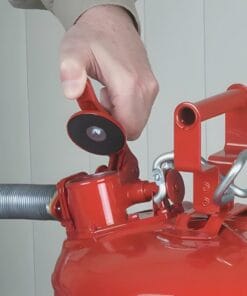 Mężczyzna obsługujący gaśnicę, trzymając rękę na uchwycie. Elementy mechaniczne są wyraźnie widoczne, co podkreśla znaczenie środków awaryjnych i bezpieczeństwa pracy w kontekście ochrony środowiska.