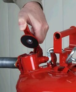 Osoba z ręką przy czerwonym gaśnicy, przygotowując ją do użycia. Ważny element bezpieczeństwa pracy i środków awaryjnych, związany z ochroną środowiska. Gaśnice są kluczowe w zapobieganiu pożarom i ochronie przed zagrożeniami.