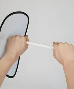 Dwie ręce trzymają przedmiot o owalnym kształcie z białą rączką, przypominający lustro lub tarczę. W przestrzeni neutralnej, skoncentrowane na bezpieczeństwie pracy oraz wpływie narzędzi na środowisko. Idealny do omawiania kwestii ochrony środowiska i bezpiecznych praktyk w pracy.