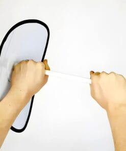 Dwie ręce trzymają okrągłe lusterko na długim uchwycie, co może być wykorzystane w kontekście środków awaryjnych w ochronie środowiska. Lusterko ma białą powierzchnię z czarną obramówką, a tło jest jasne.