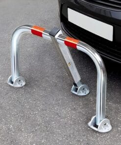 Bariera ochronna przy samochodzie, wykonana z metalu, z widocznymi ostrzegawczymi paskami w kolorze czerwonym i białym na górze. Służy do zabezpieczania miejsca parkingowego i zapewnienia bezpieczeństwa pracy w obszarach ruchu pojazdów.