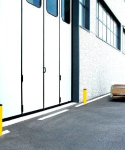 Widok na białe, podwójne drzwi magazynowe z oknami, obok żółte słupki ochronne. W tle widoczny wózek widłowy z paletą na powierzchni parkingowej. Obraz przedstawia nowoczesne środowisko pracy z naciskiem na bezpieczeństwo i organizację przestrzeni.