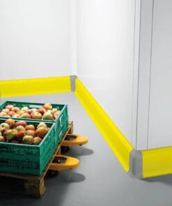 Zielone skrzynie z jabłkami na paletach, w otoczeniu z żółtymi zabezpieczeniami narożnymi. Obrazek przedstawia dbałość o bezpieczeństwo pracy i ochronę środowiska w magazynach spożywczych.
