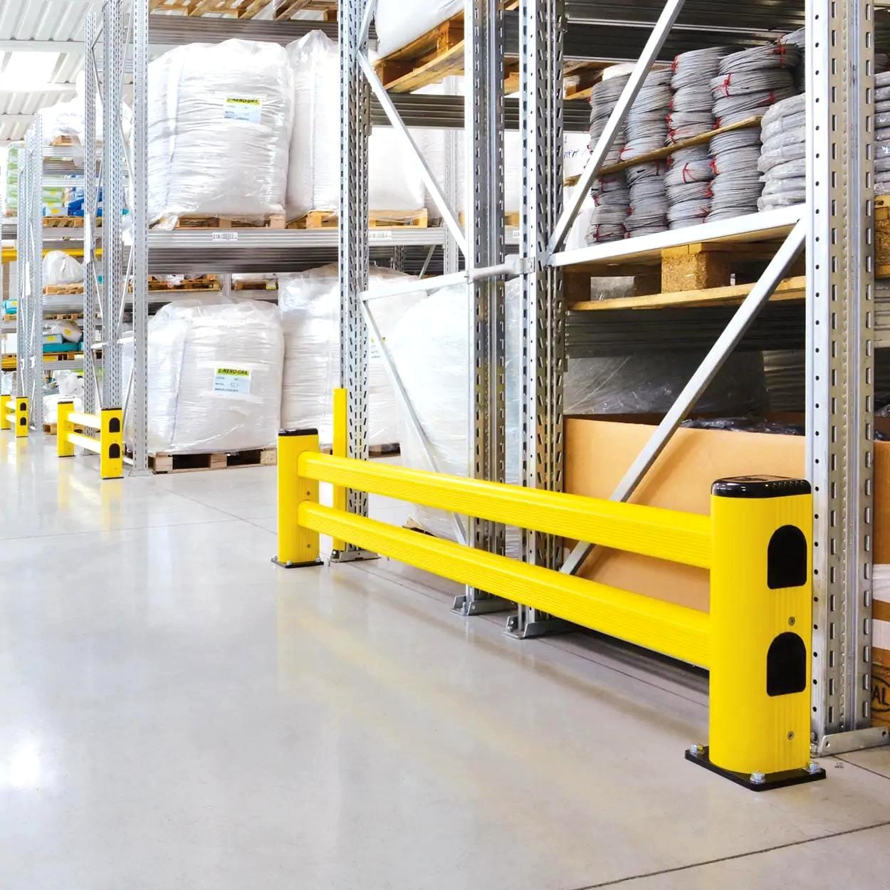 Żółta bariera ochronna w magazynie, zapewniająca bezpieczeństwo w miejscu pracy. W tle widoczne regały z workami i materiałami, co podkreśla znaczenie ochrony środowiska i bezpieczeństwa podczas przechowywania materiałów.