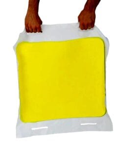 Osoba trzyma żółty podkład w białym opakowaniu. Produkt może być używany w działaniach ochrony środowiska lub jako środek awaryjny. Widoczny kształt i kolor sugerują, że jest to element zapewniający bezpieczeństwo pracy w sytuacjach kryzysowych.