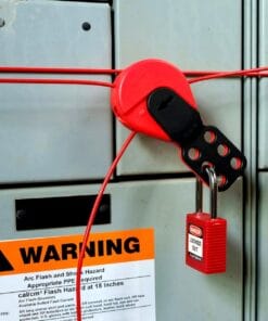 Zamek i blokada przyłączone do szafki elektrycznej, z wyraźnie widoczną etykietą ostrzegawczą. Elementy ochrony pracy i środki awaryjne na miejscu, podkreślające znaczenie bezpieczeństwa pracy w kontekście zagrożeń elektrycznych.