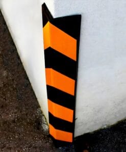 Ściana zabezpieczona żółto-czarnym narożnikiem ochronnym, służącym do ochrony przed uszkodzeniami w miejscach o dużym natężeniu ruchu. Zastosowanie takiego oznakowania wzmacnia bezpieczeństwo pracy oraz minimalizuje ryzyko wypadków w obszarze przemysłowym.