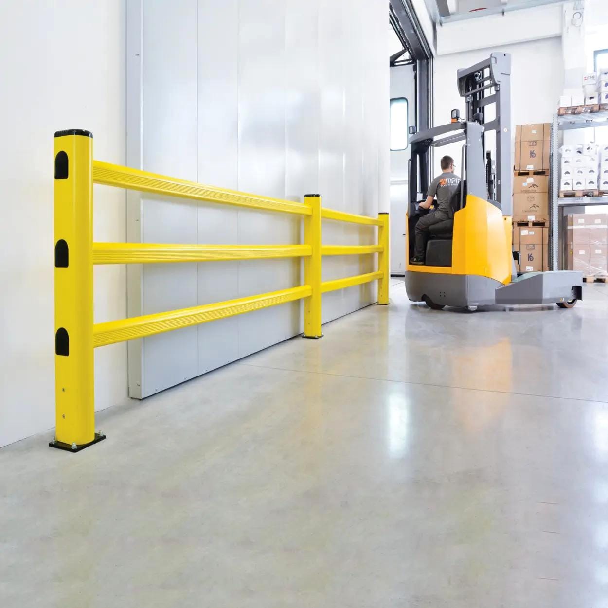 Rampa ochronna w magazynie z żółtymi barierami chroniącymi przed wypadkami, a w tle wózek widłowy, który zapewnia bezpieczeństwo pracy i efektywność operacji logistycznych.