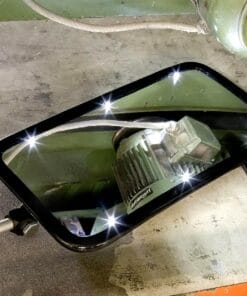 Zbliżenie na lustro inspekcyjne, które odbija silnik i kabl przemysłowy. Otoczenie w stylu przemysłowym, z zielonymi ścianami i betonową podłogą, co podkreśla kontekst bezpieczeństwa pracy i wpływu na środowisko.