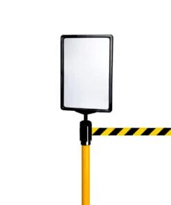 Odbicie w lustrze ostrzegawczym zamontowanym na żółtej rurze, z urządzeniem zabezpieczającym w postaci pasów ostrzegawczych w czarno-żółte paski. Elementy te są ważne w kontekście bezpieczeństwa pracy i środków awaryjnych w strefach potencjalnie niebezpiecznych.