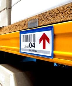 Znak wskazujący poziom 04 na regale magazynowym, z kodem kreskowym i strzałką w górę. W tle widoczne kartonowe opakowania. Przykład organizacji przestrzeni w magazynie, co wspiera bezpieczeństwo pracy oraz efektywność.