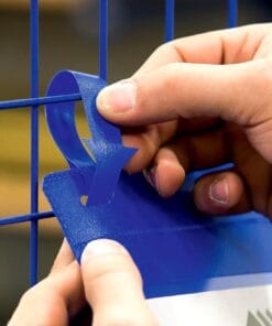 Ręka trzymająca niebieski uchwyt, mocujący etykietę do niebieskiej siatki. Elementy zabezpieczające są istotne w kontekście bezpieczeństwa pracy i organizacji przestrzeni roboczej, co wspiera efektywne zarządzanie i ochronę środowiska.