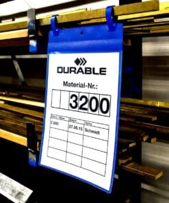 Widok oznaczenia materiału na niebieskiej etykiecie w magazynie, z numerem 3200. Etykieta zawiera dane dotyczące materiału, takie jak ilość, datę i nazwisko, co jest istotne dla zarządzania zasobami. Zastosowanie systemów oznaczeń wspiera efektywność w procesach logistycznych i bezpieczeństwo pracy.