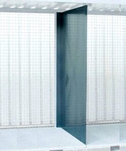 Przezroczysta ścianka wykonana z materiału kompozytowego w nowoczesnym pomieszczeniu, z metalową siatką w tle, reprezentująca innowacyjne rozwiązania w architekturze i ochronie środowiska, które wspierają bezpieczeństwo pracy oraz ekologię.