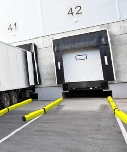 Widok na rampy załadunkowe w magazynie, z naczepą ciężarówki oraz żółtymi barierami zabezpieczającymi. Obiekt dobrze oświetlony, z numerami 41 i 42 na ścianie budynku, co podkreśla organizację przestrzeni i bezpieczeństwo pracy.