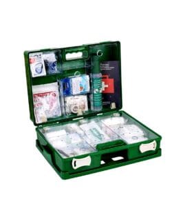 Zielona apteczka pierwszej pomocy, otwarta, ukazująca różnorodne materiały medyczne, takie jak bandaże, opatrunki i płyny dezynfekujące, co podkreśla znaczenie bezpieczeństwa pracy oraz skutecznych środków awaryjnych w sytuacjach kryzysowych.