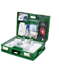 Zestaw pierwszej pomocy w zielonej plastikowej skrzynce, zawierający różne środki opatrunkowe, bandaże, narzędzia medyczne oraz instrukcje, istotny w sytuacjach awaryjnych dla zapewnienia bezpieczeństwa pracy i ochrony zdrowia.