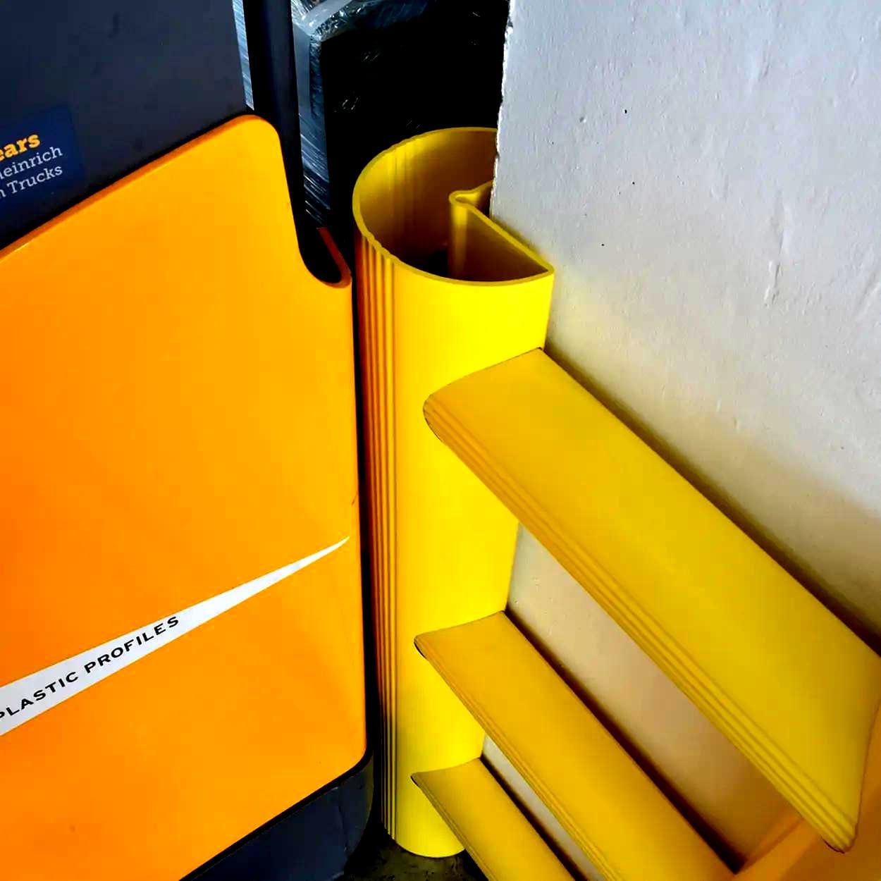 Widok kolorowych, żółtych plastikowych profili oraz elementów ochronnych współczesnych systemów zabezpieczeń w miejscu pracy. Elementy te mogą być używane do poprawy bezpieczeństwa pracy oraz ochrony przed wypadkami, podkreślając znaczenie ochrony środowiska i ekologicznym podejściu w projektowaniu przemysłowym.