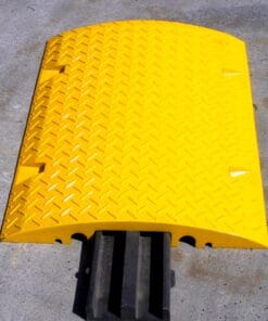 Żółta płyta ochronna z fakturowaną powierzchnią, przeznaczona do zabezpieczania kabli i przewodów na powierzchniach przemysłowych. Element zwiększający bezpieczeństwo pracy i minimalizujący ryzyko potknięć, umieszczony na betonowym podłożu. Idealny do zastosowań w ochronie środowiska i zgodności z normami bezpieczeństwa.