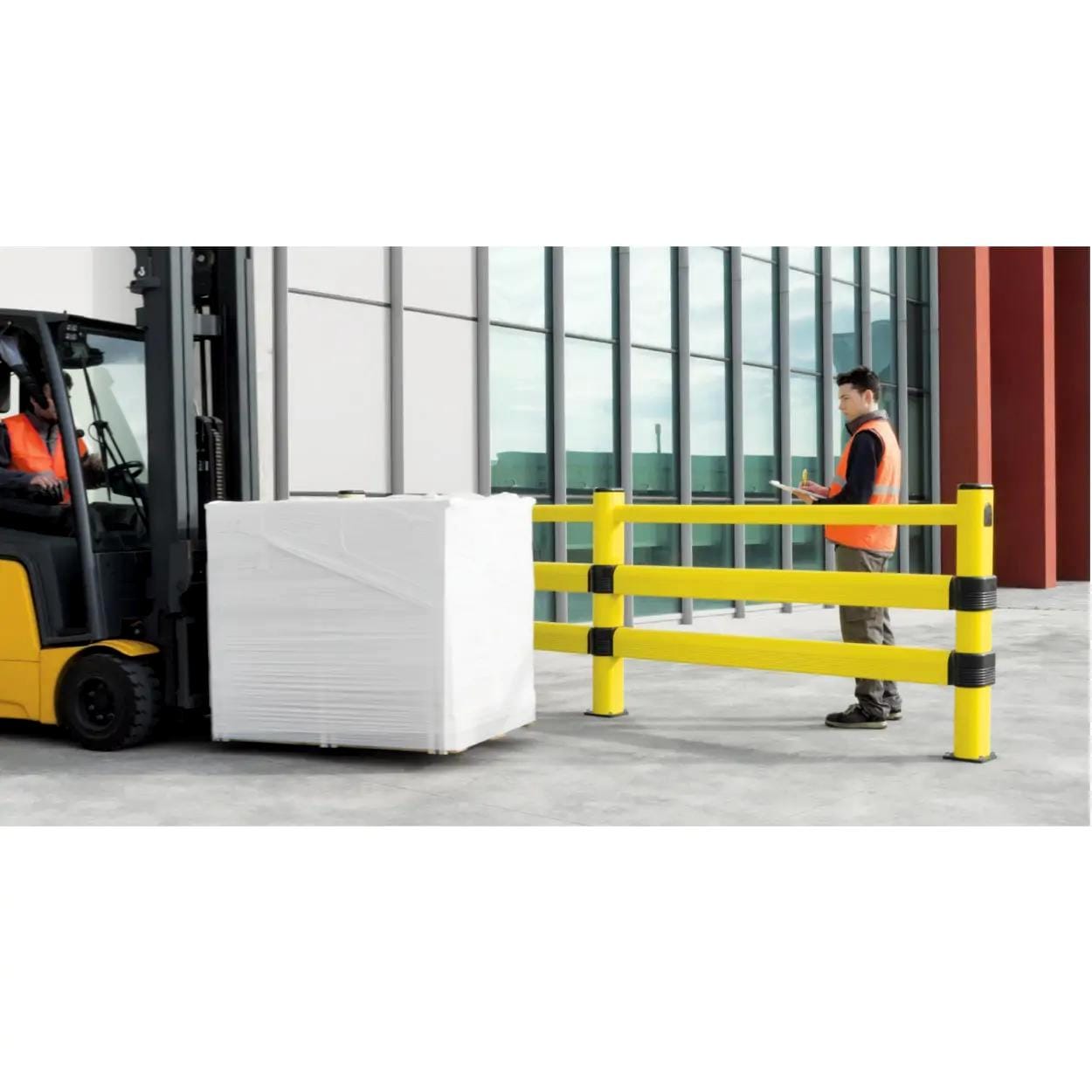 Pracownik w kamizelce odblaskowej obserwuje wózek widłowy transportujący ładunek obok żółtej barykady. Scena ilustruje środki bezpieczeństwa pracy w magazynie, zapewniające ochronę podczas operacji transportowych.