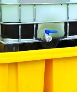 Zbiornik z płynem chemicznym umieszczony na żółtej podstawie, z zaworem odpływowym w niebieskim kolorze, służący do przechowywania substancji wymagających monitorowania w kontekście bezpieczeństwa pracy i ochrony środowiska.